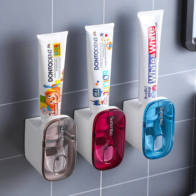 Three toothpaste tubes on a toothpaste holder against a tiled bathroom wall.